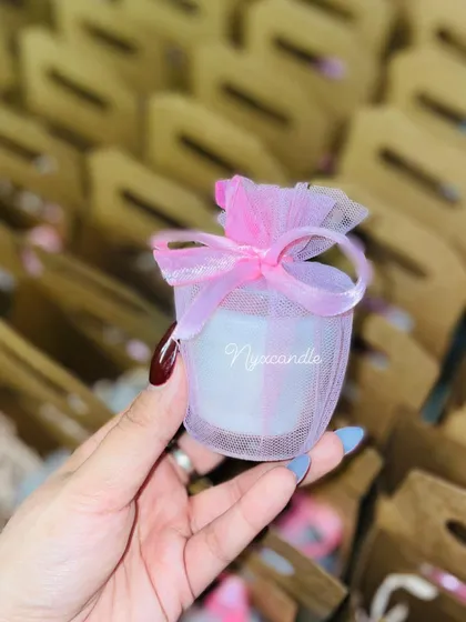 A personalized mini scented candle in a glass jar, wrapped in net for a wedding favor.