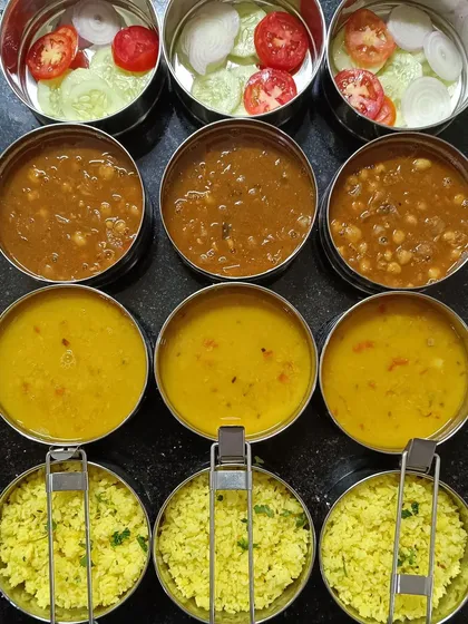 Packing in full swing. This image captures the process of portioning out lemon rice, dal, chana masala, and salad into individual bowls for my subscribers.