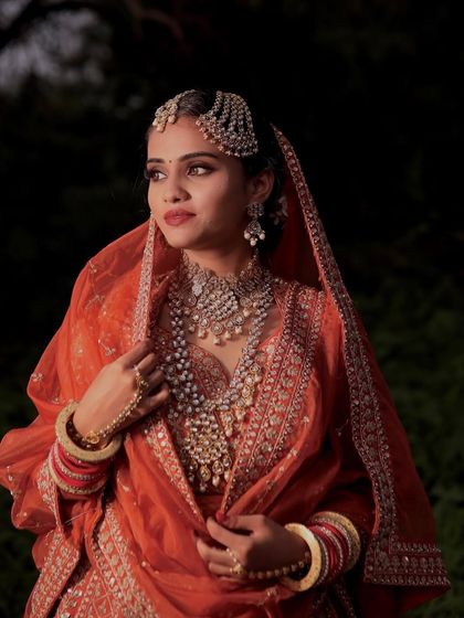 The bride's regal pose showcases her complete look. The makeup enhances her sharp features, creating a look of timeless beauty.