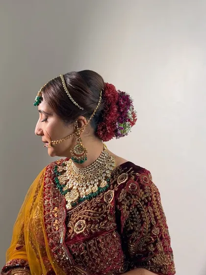 A side view of this bride's stunning floral bun, created for her Nikkah ceremony. The rich colors of the flowers complement her velvet outfit perfectly.
