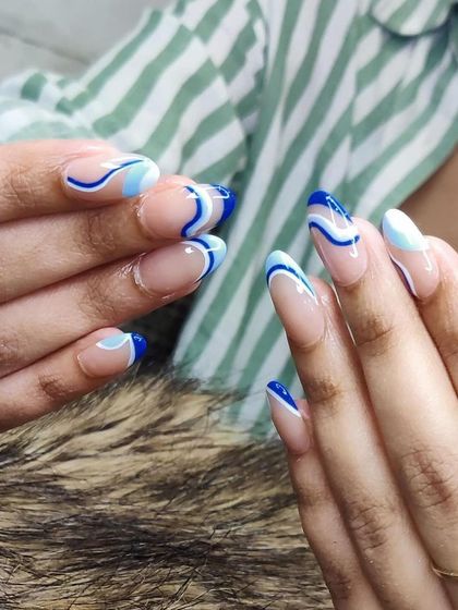 A cool, abstract design with waves of blue and white on a sheer nude base. This look is modern and artistic.