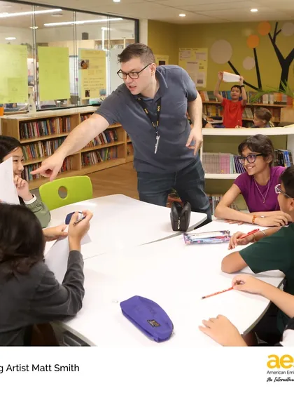 Visiting artist Matt Smith engages with a group of middle school students, inspiring them with his passion for comics and storytelling. These interactions make learning dynamic and memorable.