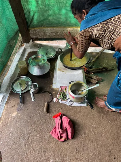 The final touches being added to a pot of dal, cooked over an open flame. You can almost smell the delicious aroma of a home-cooked meal.