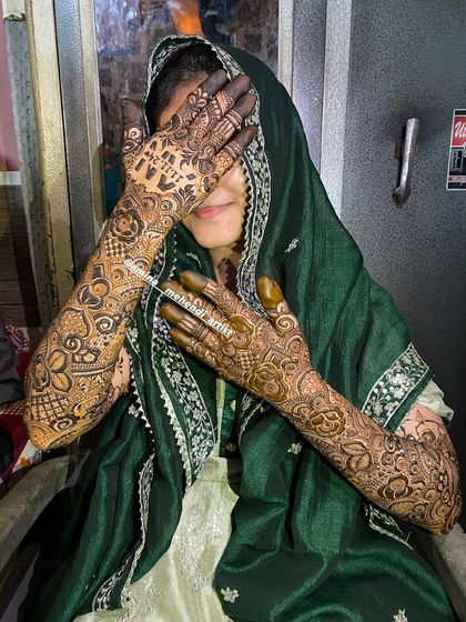 A happy, candid moment with the bride, showing her beautiful full-arm mehendi.