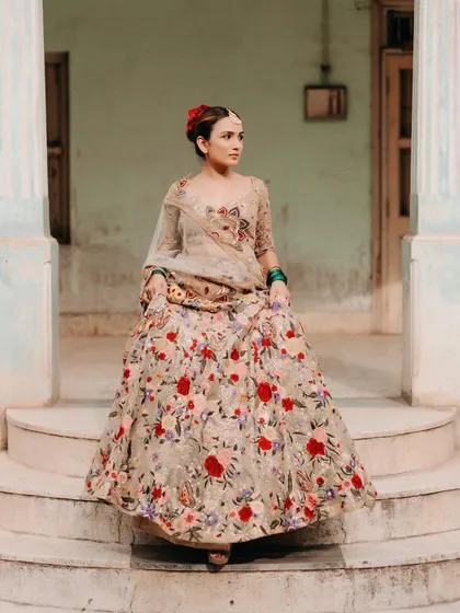 A full-length shot of our virtual bride Priya. The floral embroidery on her lehenga stands out beautifully against the ancestral home's architecture, creating a stunning contrast.
