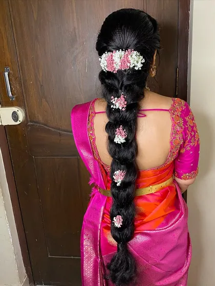 A close-up of the messy braid with pink and white flowers. This hairstyle is perfect for a bride who wants a soft, romantic, and natural look.