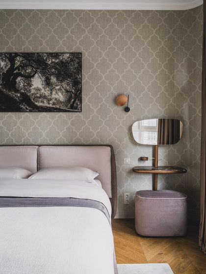 The right combination of wallpaper, a fabric headboard, and a matching dresser gives an "aww" look to your bedroom. This design uses a subtle patterned wallpaper to create a serene and stylish space.