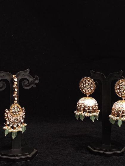 This rental set includes beautiful jhumkas with mint green enamel work and a matching maang tikka, perfect for a coordinated look.