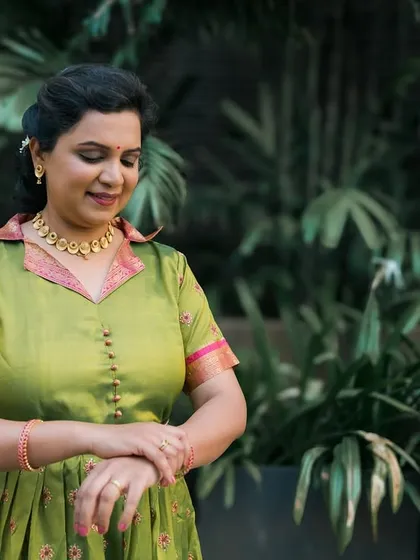 A candid-style portrait of a woman in a green dress, looking down with a gentle smile.