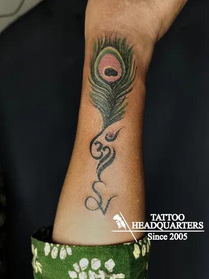 A creative design combining a peacock feather with the Om symbol and the letter 'V', merging personal and spiritual elements.
