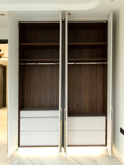 The interior is just as important as the exterior. This wardrobe opens to reveal ample hanging space and deep drawers, all crafted with a premium wood finish.