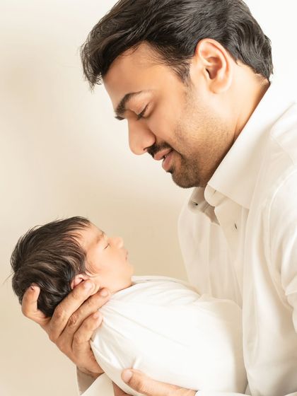 A father gazes at his sleeping newborn with pure adoration. This close-up shot in warm, natural light highlights the quiet, tender moments that define new fatherhood.