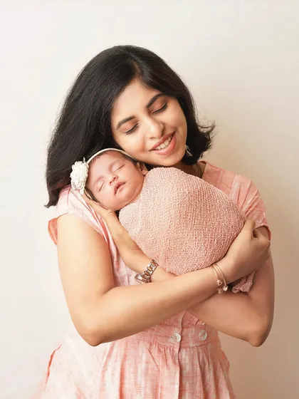 A mother's love shines through as she holds her sleeping newborn. The soft lighting and her gentle smile create a portrait of pure tenderness.