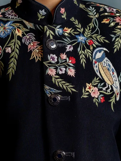 A close-up on the exquisite craftsmanship of our signature embroidered Indo-western jacket. The detail in every stitch of the bird and floral pattern is what sets our couture apart.