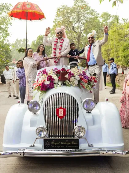 A classic groom's entry in a vintage white Rolls-Royce, a timeless and elegant choice for a grand arrival.