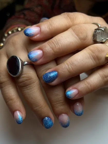 Dipped in ocean dreams. This look features a beautiful glitter fade, with sparkling blue reflective glitter concentrated at the tips and blending into a natural nude base for a mermaid-inspired effect.