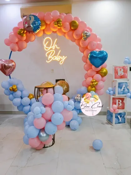 A beautiful 'Oh Baby' gender reveal setup with a balloon ring, neon sign, and 'BABY' blocks.