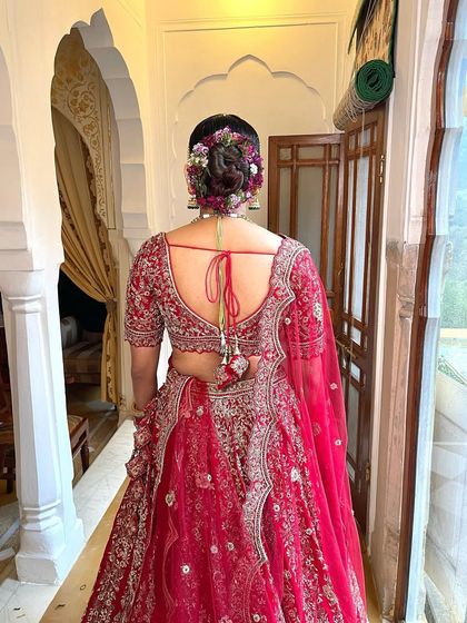 A full length view of the bride from the back, showing how the beautiful floral bun complements her traditional red lehenga.