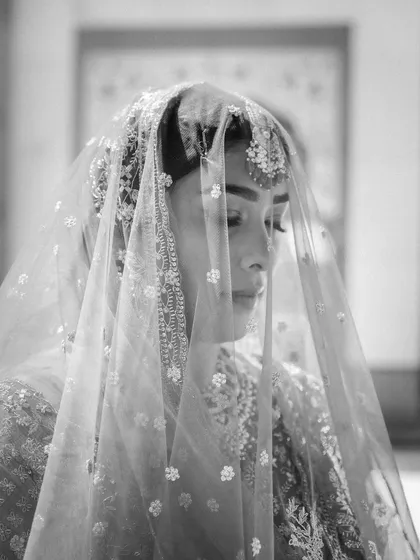 A delicate and artistic black and white portrait of a Sikh bride under her veil. The soft focus and lighting create a timeless and emotional image.