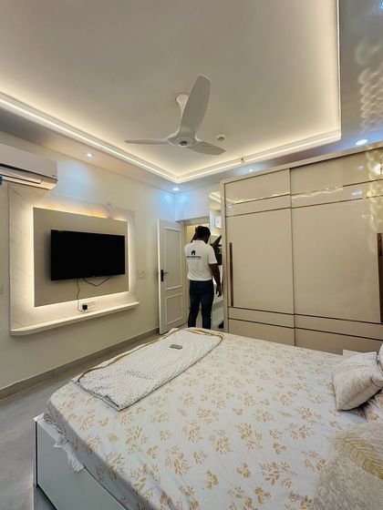 A completed bedroom at JM Florence, featuring a sliding wardrobe and a simple backlit TV panel.