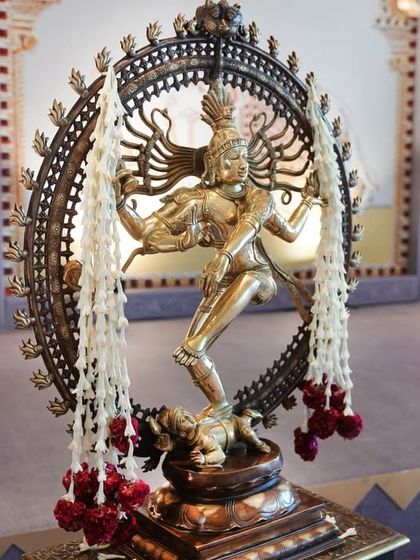 The Nataraja statue seen from a different angle, set against the backdrop of the grand entrance structure. The combination of divine sculpture and architectural elements creates a powerful and welcoming first impression.