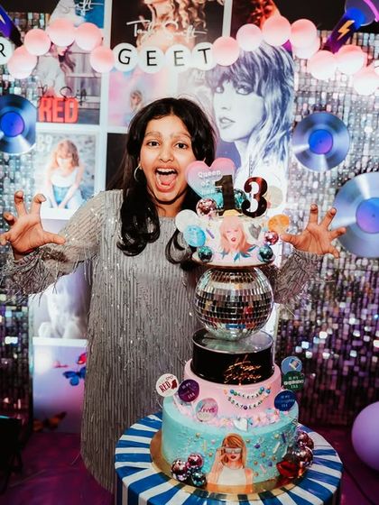The birthday girl, Geet, looking ecstatic with her amazing Taylor Swift themed cake, complete with a disco ball and different "eras" represented.