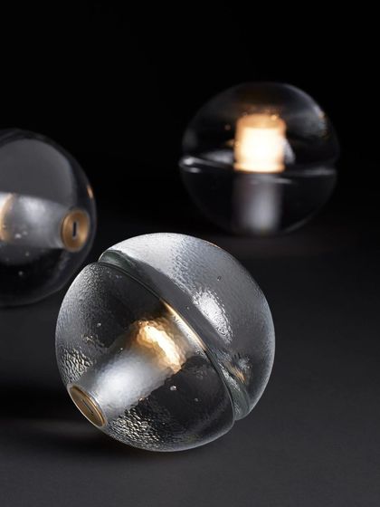 Three clear glass 14p lamps are arranged together, showcasing the slight variations that result from the hand-poured glass process.