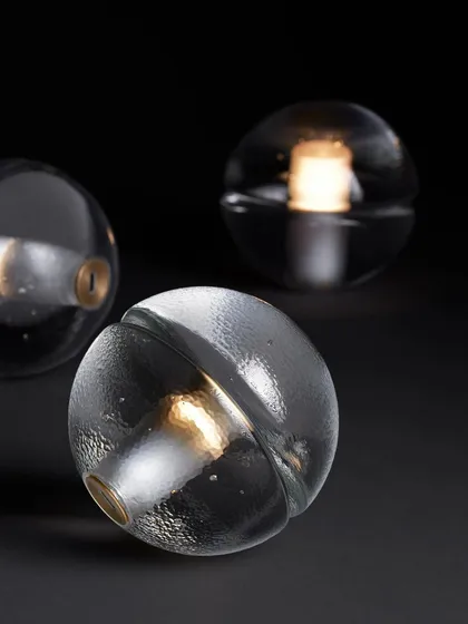 Three clear glass 14p lamps are arranged together, showcasing the slight variations that result from the hand-poured glass process.