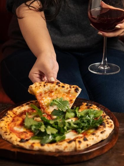 An ode to the simple pleasure of a perfect slice of pizza. Paired with a glass of red wine, it's a sublime dance of flavors and textures, meant to be savored.