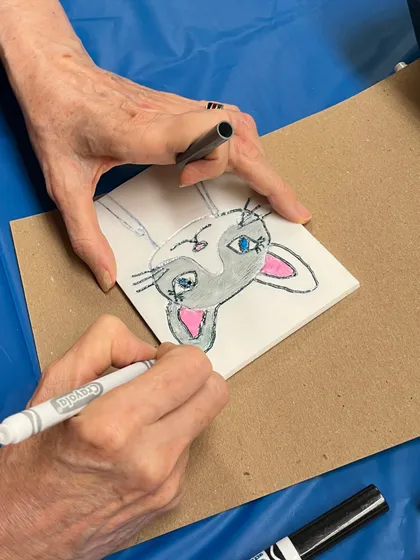 An adult participant drawing a cute cat for her printmaking design. Our workshops are a great activity for both kids and adults to enjoy together.