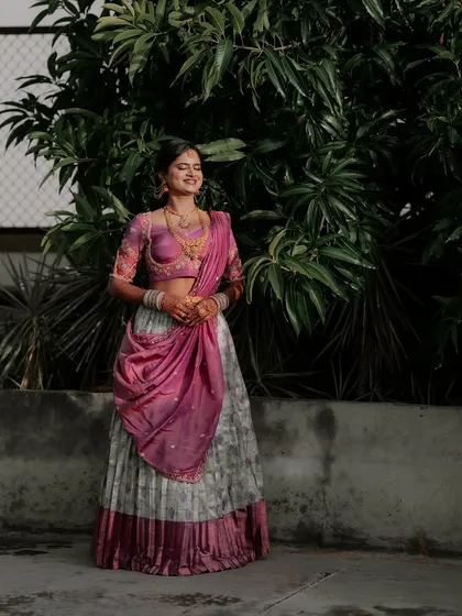 A modern take on tradition. This client is glowing in her custom Langa Dhawani, which pairs a contemporary grey pleated skirt with a vibrant pink embroidered blouse and dupatta.
