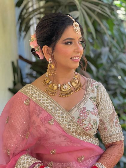 A beautiful bride with a soft, romantic updo adorned with fresh pink flowers.