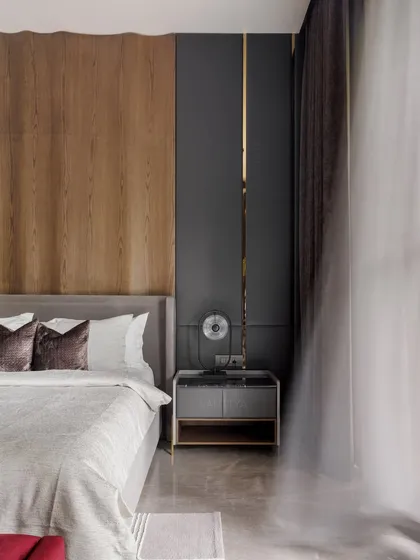 This shot highlights the material palette of the son's bedroom: warm wood paneling, a dark grey accent wall with a brass inlay, and soft, sheer curtains that diffuse the natural light.