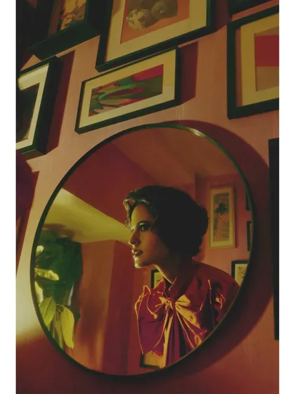 From 'Chapter 4: Gallery of Expectations'. The styling introduces a bold red blouse with a large bow, reflecting a shift towards a more hopeful and assertive future. The mirror reflection adds a layer of complexity.