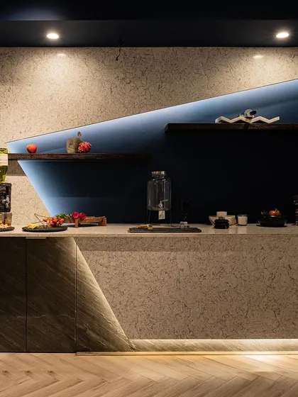 Our expertise in material and lighting is showcased in this custom bar counter. The combination of a textured stone facade, a sleek marble top, and integrated warm LED lighting creates an ambiance of modern elegance and highlights the displayed items beautifully.