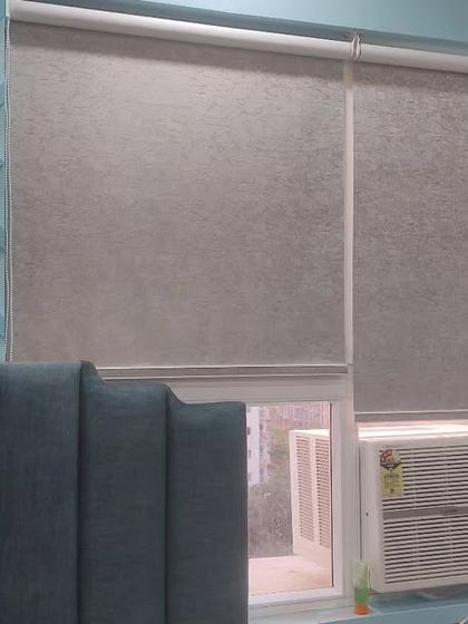 Simple and functional fabric roller blinds installed in a bedroom. These are a popular choice for a clean, minimalist look and are available in many colors.