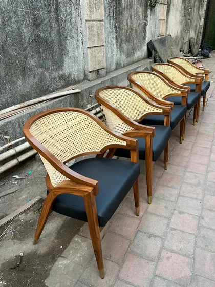 A set of my mid-century dining armchairs with black leatherette seats and caned backs, lined up for delivery to a restaurant client. The brass-capped legs add a touch of elegance.