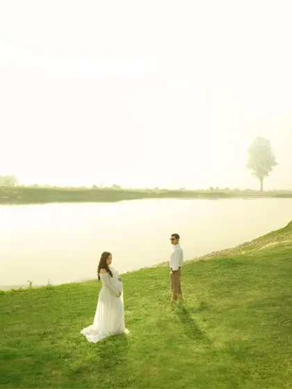 A minimalist and serene portrait of the couple by the lake. The bright, hazy light creates a dreamy, ethereal quality, focusing on their presence in the vast, peaceful landscape.