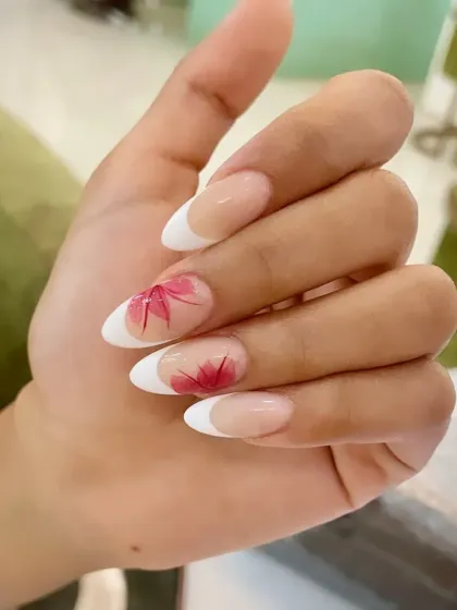 A single-hand view of the elegant French manicure with delicate red floral accents on almond-shaped nails.