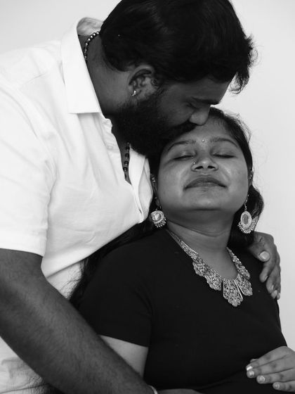 An intimate and emotional black and white shot. A gentle kiss on the forehead from her partner makes this a deeply personal and loving maternity portrait.