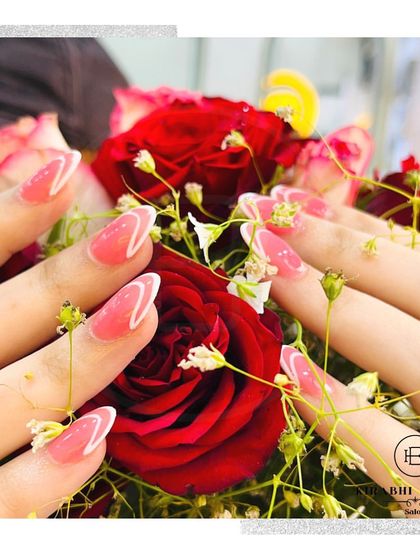 A creative shot of the pink and white abstract French manicure, nestled in a bed of fresh flowers.