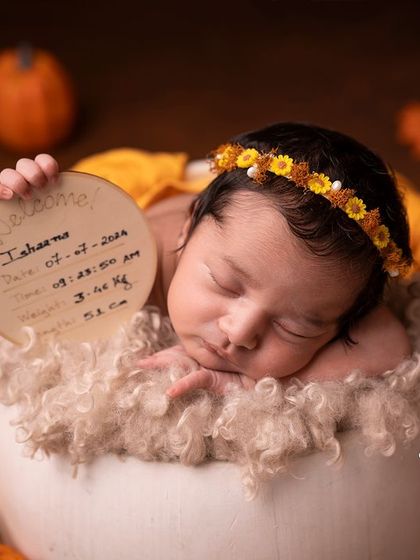 A newborn girl holding a birth announcement plaque, a beautiful way to share the details of her arrival.