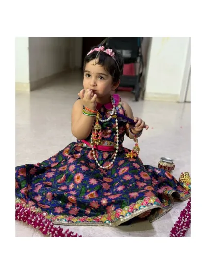 This little girl is ready for a festive puja in her beautiful navy blue phulkari-style embroidered lehenga. The intricate details and bright colors make it a standout piece.