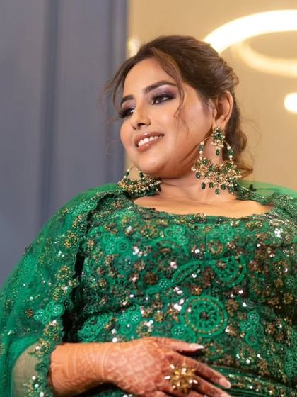 A confident pose in her vibrant green Sangeet outfit. The makeup is designed to be glamorous and photo-ready from every angle.