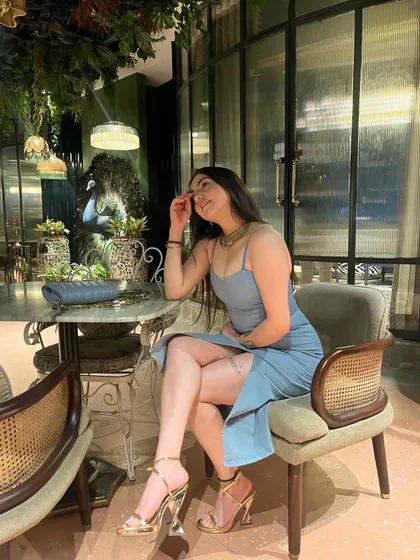 A full-length shot in a blue dress, seated in a chic corner of a restaurant, showing the elegant side of an evening out.