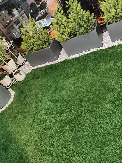I transformed this city rooftop into a chic green oasis. The artificial grass installation provides a beautiful, soft surface underfoot, complemented by modern planters and lighting, making it the perfect spot for evening relaxation with a view.