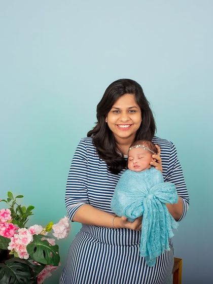 A happy new mother holds her baby in the studio. The simple setup and her bright smile make this a heartwarming and classic portrait.