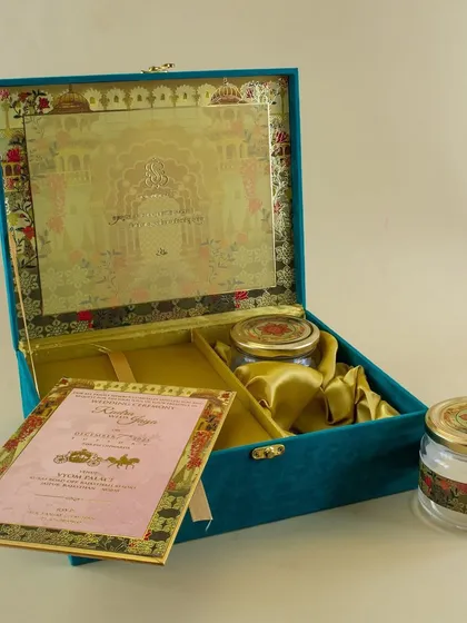 For a truly grand statement, I create custom boxed wedding invitations. This teal velvet box opens to reveal the main invitation card, separate inserts for different events, and custom-fitted compartments for gifts like dry fruits or sweets.