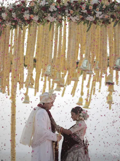 The exchange of garlands under a shower of delicate petals. The hanging floral decor with bells adds a traditional and auditory element to this beautiful ritual.