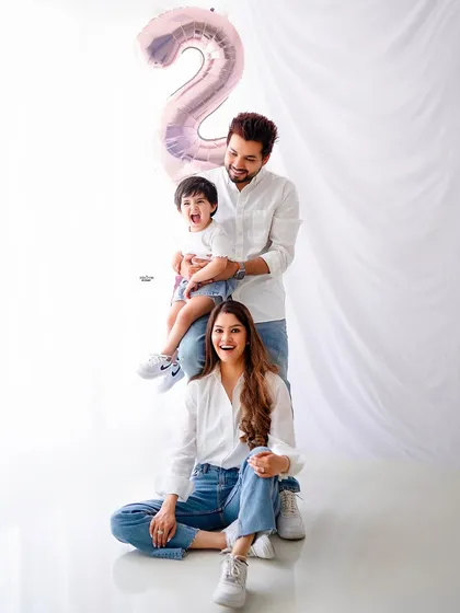 A fun and dynamic family pose. This "family totem pole" is a great way to capture a playful moment, celebrating their son's second birthday with a number 2 balloon.
